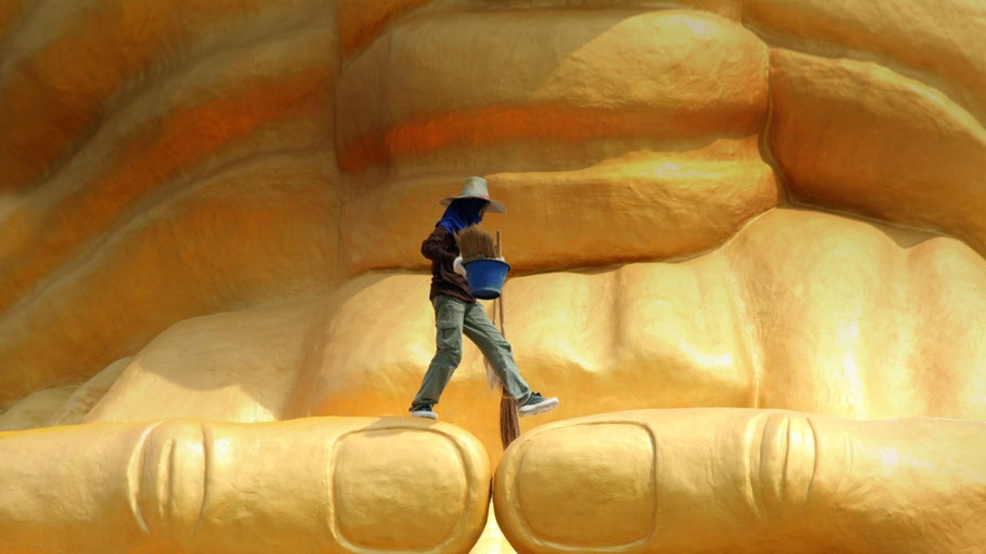 泰国大城府佛像上的清洁工人