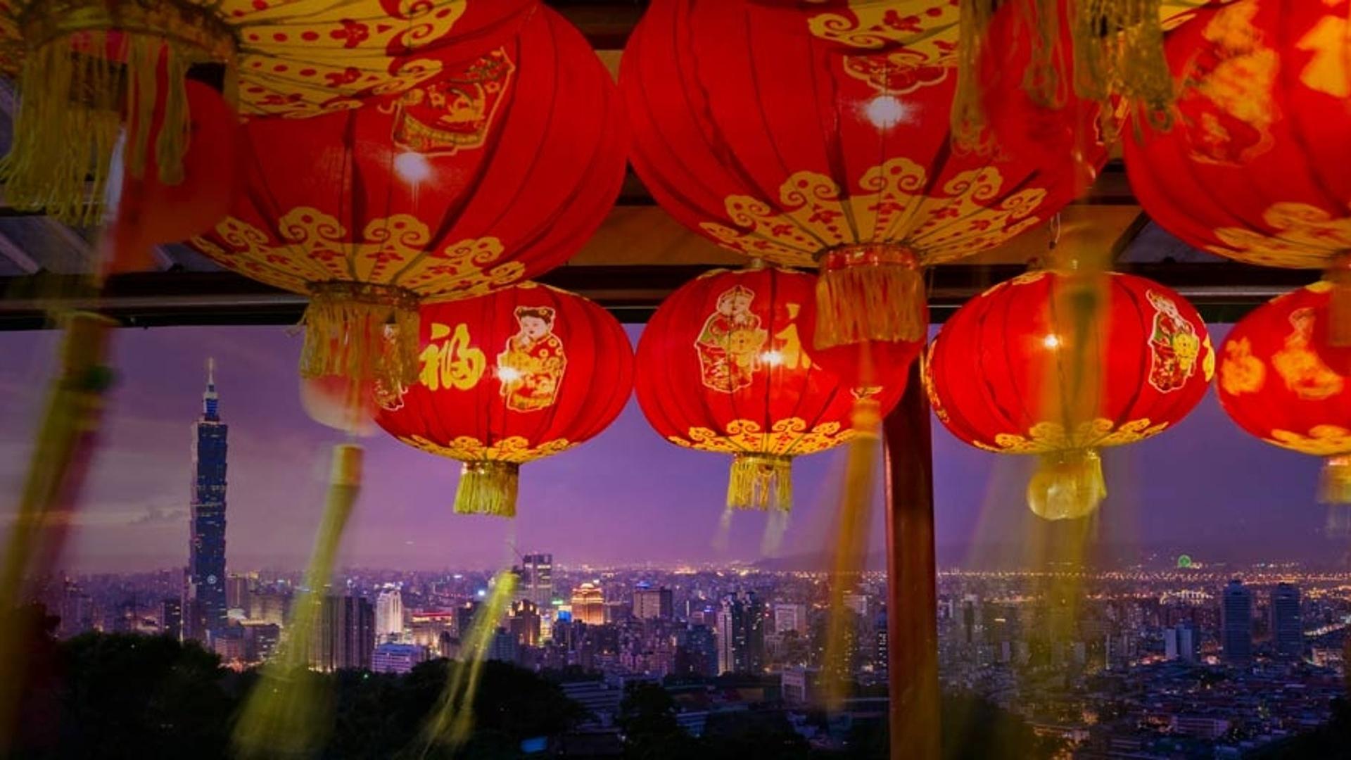 从挂满灯笼的寺庙看向远处的台北101