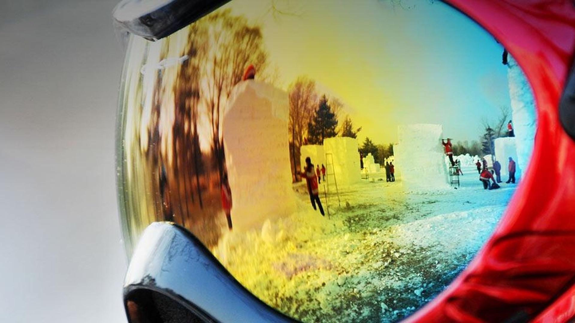 于2012年1月3日在哈尔滨举行的第18届全国雪雕大赛中，雪雕选手的护目镜反射出参赛者们的制作场景