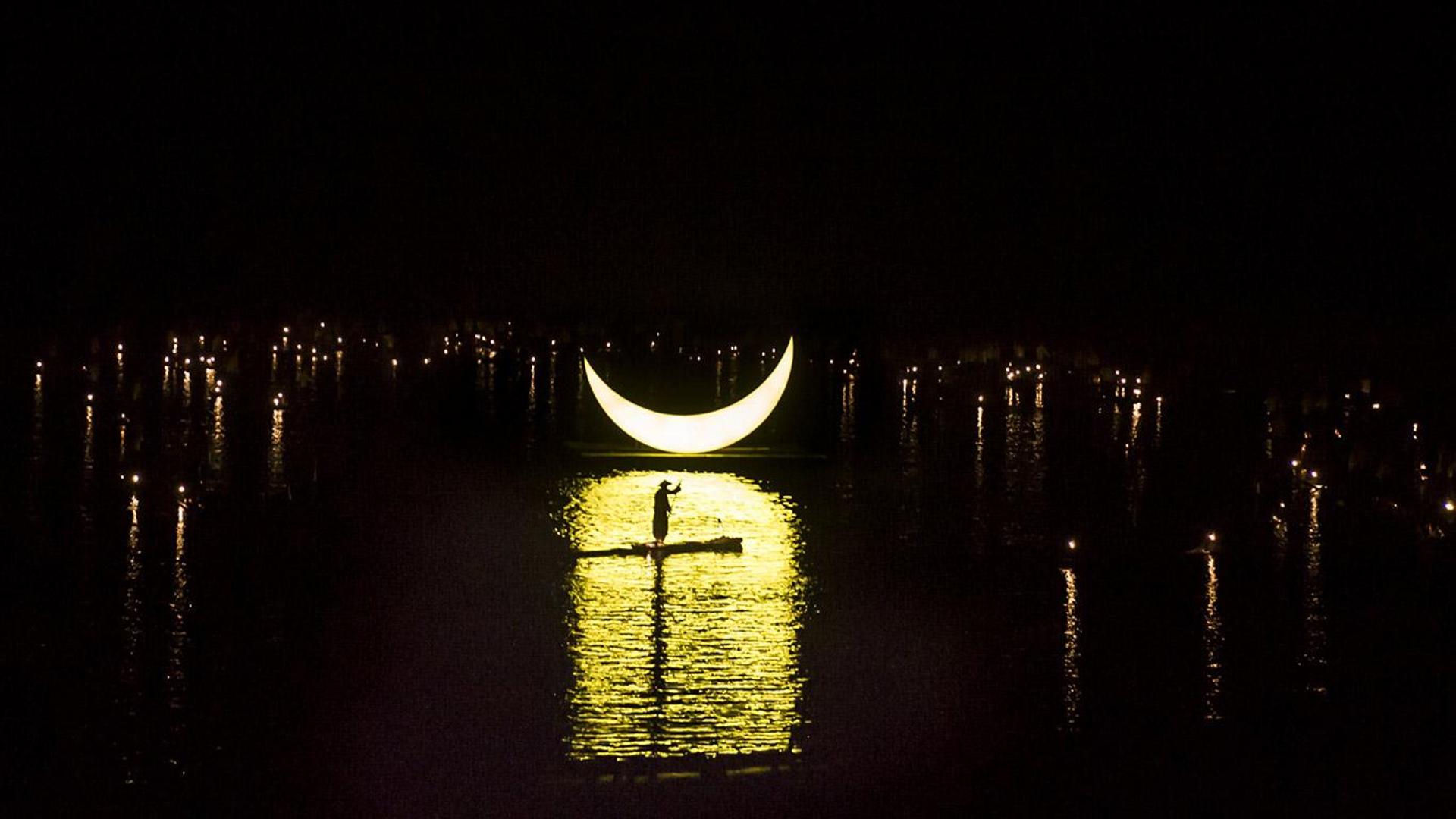 一轮新月下，头戴斗笠的表演者